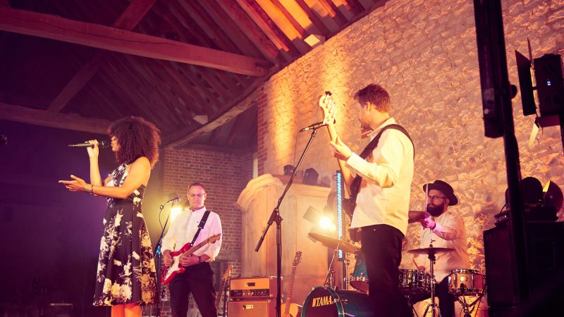 Side on shot of AKA playing at Bury Court Barn against the limestone wall - Live Wedding Band | Surrey wedding entertainment | live band for wedding | Live band for wedding reception | AKA Party Band