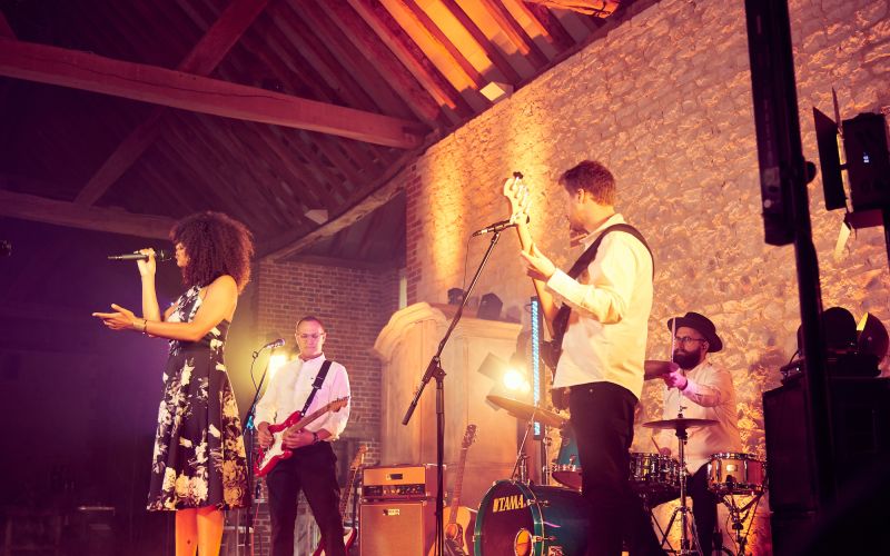 Side on shot of AKA playing at Bury Court Barn against the limestone wall - Live Wedding Band | Surrey wedding entertainment | live band for wedding | Live band for wedding reception | AKA Party Band