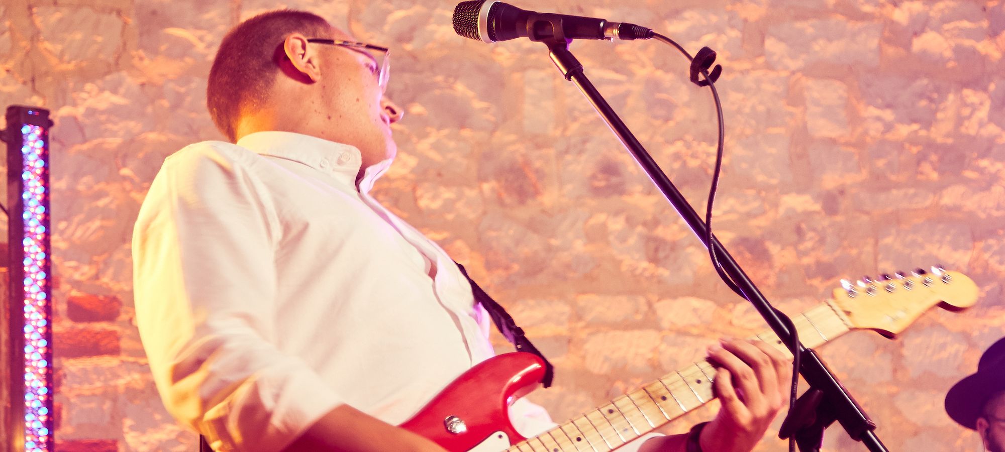 Guitarist with red Fender Stratocaster at barn venue in Hampshire - Live Wedding Band | How to book a wedding band | live bands for wedding | Live band wedding cost | how much is a live band for a wedding | AKA Party Band